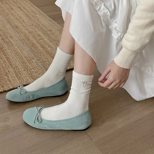 Detail of cable knit crew socks with metallic bow charm paired with blue ballet flats