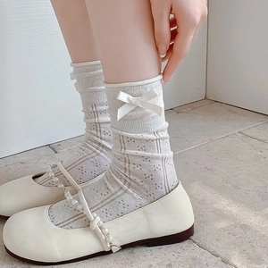 Close-up of white mesh bow socks with Mary Jane shoes and elegant pearl details