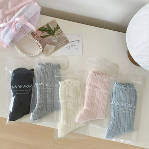 Detail of five pairs of ruffled mesh socks in pastel colors with floral knit patterns
