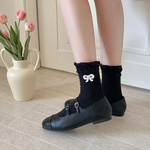 Details von Mary Jane Schuhen und schwarzen Socken mit weißem Schleifen-Stickerei