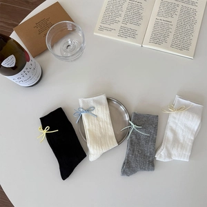 Detailed view of four pairs of ribbed socks with colorful bow accents on a white desk