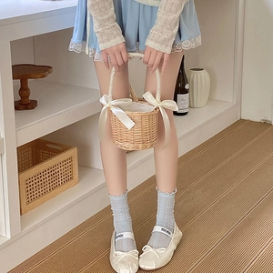 Detail of woven wicker basket with white satin bows held by a model in lace socks