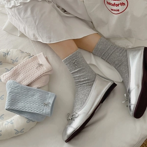 Detailed close-up of cable knit crew socks with delicate silver ribbon bow accessories