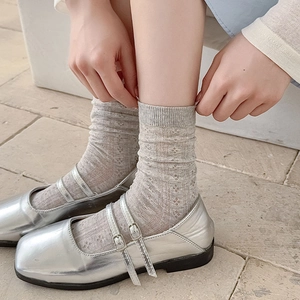 Detail of silver Mary Jane shoes paired with light gray hollow out knit crew socks