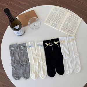 Flat lay of mesh knit socks set with delicate bow knots on a white decorative table