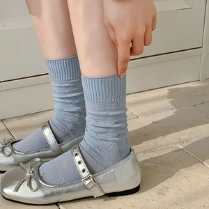 Detailed view of light blue ribbed mesh socks with floral eyelets and silver Mary Jane shoes