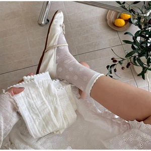 Close-up of white mesh lace socks with delicate double ruffle edges and polka dot pattern