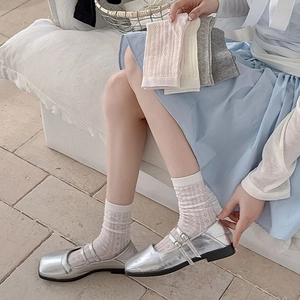 Detailed view of hollow lace socks in various pastel colors with silver Mary Jane shoes
