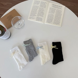 Detail of four assorted ribbed socks with delicate bow ties on a minimalist background
