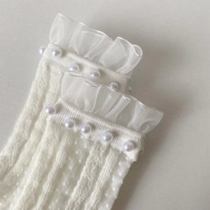 Détail de bordures en tulle à volants et perles sur des chaussettes blanches