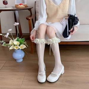 Detail of white lace knee-high socks with double ruffles and sweet ribbon bow accents