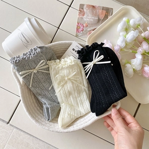 Gros plan de chaussettes ajourées avec perles et nœuds dans un panier au style élégant