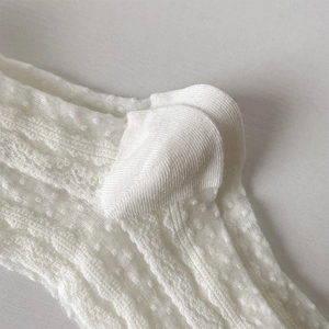 Détail macro de chaussettes en tulle blanc montrant le talon renforcé et la maille gaufrée