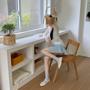 Detail of grey mesh ruffled socks worn with white ballet flats and a straw basket
