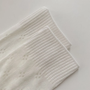 Close-up of white ribbed knit socks with delicate hollowed-out pointelle star patterns