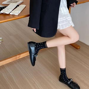 Détail de chaussettes noires à pois blancs avec bordure en dentelle et chaussures