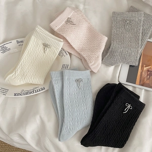 Detail view of knit socks with cable pattern and delicate silver metal bow pendants