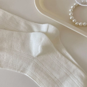 Detailaufnahme weißer gerippter Baumwollsocken mit elegantem Perlen-Hintergrund