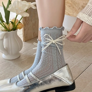 Gros plan détaillé des chaussettes en résille bleu clair avec nœud perlé et bords froufrous