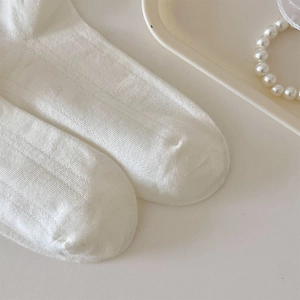 Nahaufnahme weißer gerippter Stricksocken mit weicher Baumwolltextur und elastischer Form