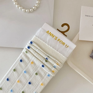 Gros plan de chaussettes blanches à pois colorés et bordure en dentelle délicate