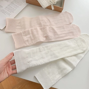 Close-up of pink and white hollow-out mesh crew socks on a wooden tray decor