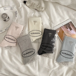 Flat lay of cable knit crew socks with metal bows in pastel pink, beige and grey