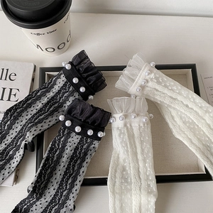 Détail de chaussettes en tulle transparent avec perles décoratives et bord à volants