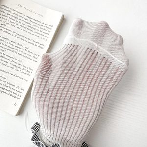 Détail de chaussettes en tricot côtelé blanc crème avec un joli nœud à carreaux noir et blanc