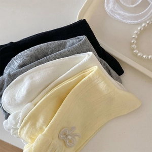 Detail von süßen Rüschensocken mit weißen Schleifen und Perlen in eleganter Umgebung