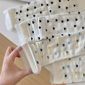 Détail de chaussettes en coton crème avec broderies de cœurs colorés et bordure dentelle