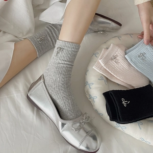 Detail of cable knit crew socks featuring elegant silver metal bow charms in four colors