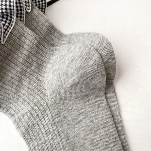Gros plan de chaussettes grises avec volants pied-de-poule et détails de nœuds