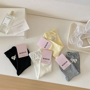 Detailaufnahme süßer Rüschensocken mit Perlenbogen-Akzenten und eleganter Markenverpackung