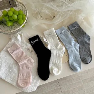 Detalle de calcetines de rejilla con delicados lazos en rosa, azul y tonos neutros