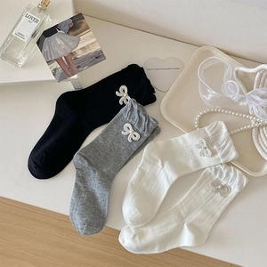 Detail von süßen Rüschensocken mit Perlschleifen in Schwarz, Grau und Weiß Tönen