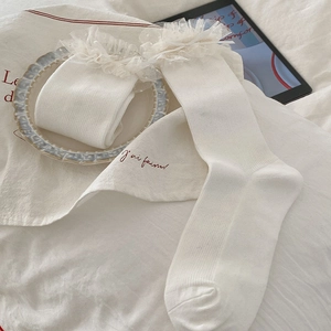 Détail de chaussettes côtelées blanches avec bordure en dentelle et nœud en ruban de soie