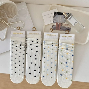 Détail de quatre paires de chaussettes blanches en dentelle à motifs cœurs et pois mignons