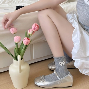 Detail von grauen Rüschensocken mit weißen Schleifen und silbernen Mary Jane Schuhen
