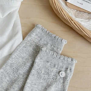 Detail of grey mesh knit socks with floral hollow patterns and white button accents