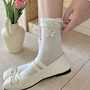 Detail von cremefarbenen Rüschensocken mit Schleifen zu Mary Jane Schuhen und Tulpen