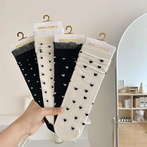 Gros plan de chaussettes à bordure en dentelle avec motifs cœurs et pois, noir et beige