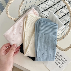 Detail of five pairs of hollow knit mid-calf socks in pastel colors with mesh patterns