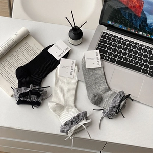 Détails des bords volantés à carreaux et nœuds sur chaussettes en noir, blanc et gris