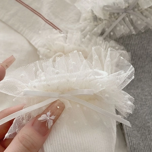Détail de chaussettes en coton blanc avec dentelle en mesh à pois et nœud en satin