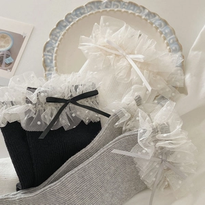 Détails des volants en dentelle et nœuds sur des chaussettes noires blanches et grises