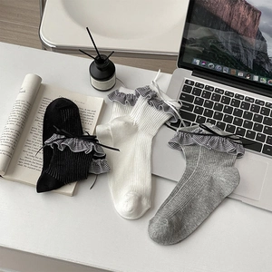 Détail de chaussettes en tricot avec bordures à carreaux et petits nœuds en couleurs neutres