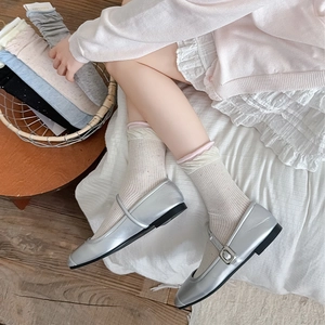 Detail of silver Mary Jane shoes paired with colorful ribbed knit crew socks for women