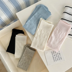 Detail of knit hollow socks showing delicate diamond patterns and ribbed cuffs in pastel colors