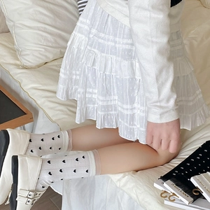 Détail de chaussettes blanches à cœurs noirs et bordure en dentelle rose clair